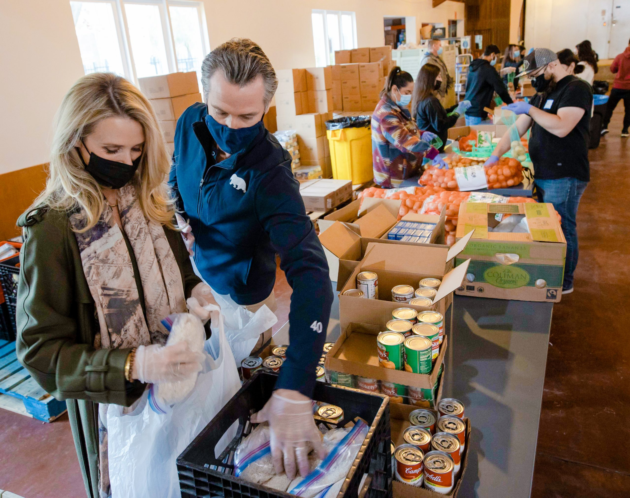 Close-up of Governor Newsom and First Partner Siebel Newsom Packaging Thanksgiving Food Boxes at Sacramento's River City Food Bank