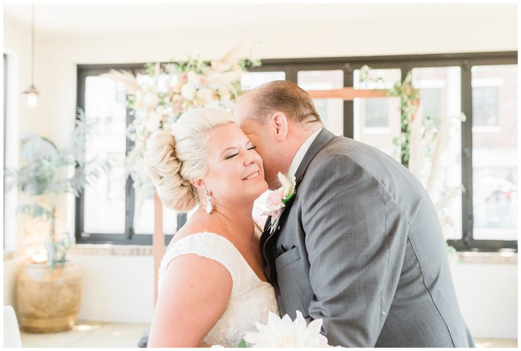 Groom kissing the bride on the cheek at their wedding at Teak Restaurant Red Bank.