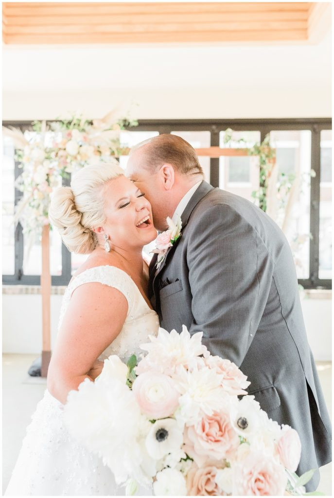 Groom whispering to the laughing bride during their Red Bank Teak wedding photoshoot.