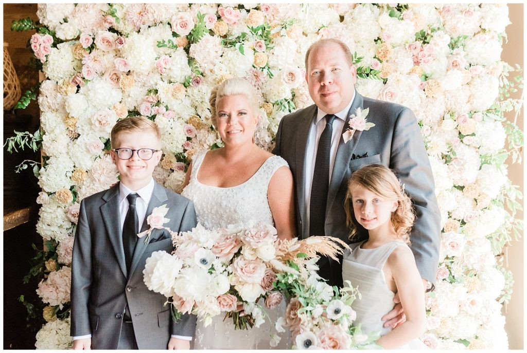 Bride and groom posing with their children for a family photo at Teak Red Bank.