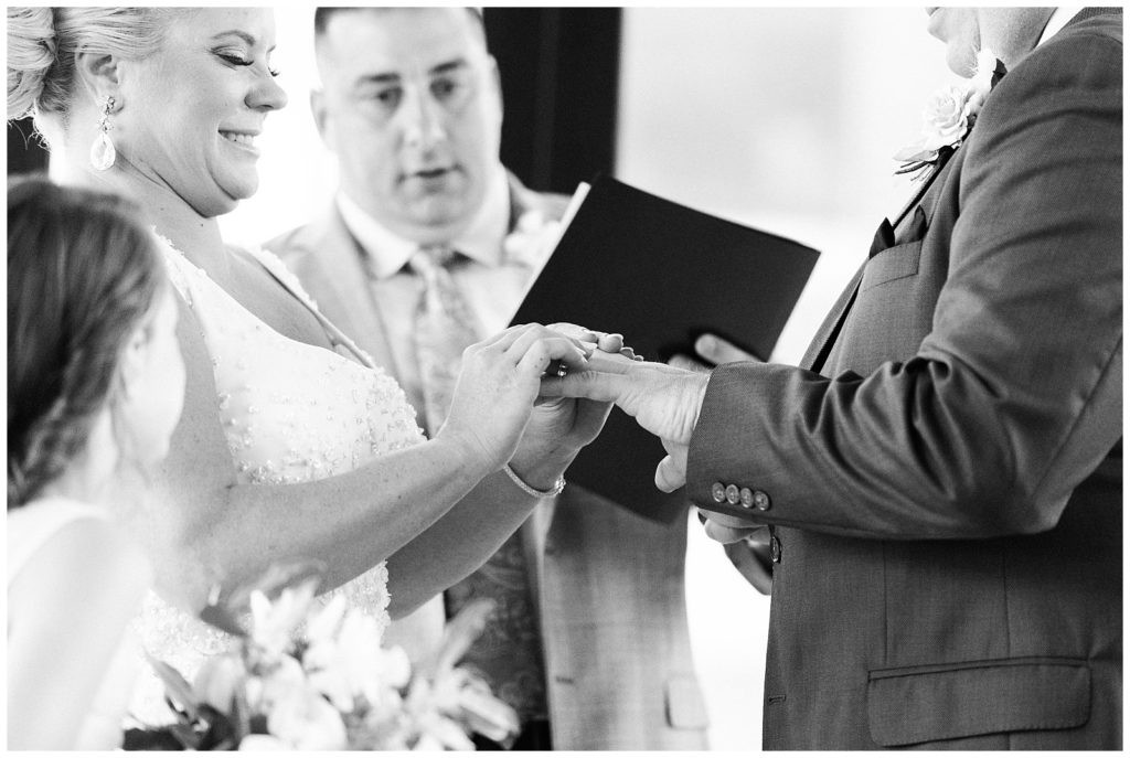 Bride placing the groom's wedding band during the ceremony at Teak Red Bank.