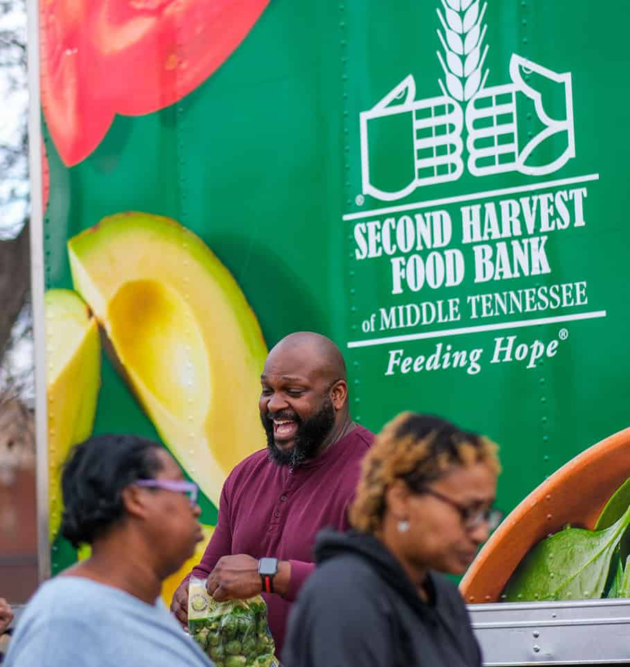 Smiling volunteers loading boxes into a truck, representing the collaborative effort at 2nd Harvest Food Bank