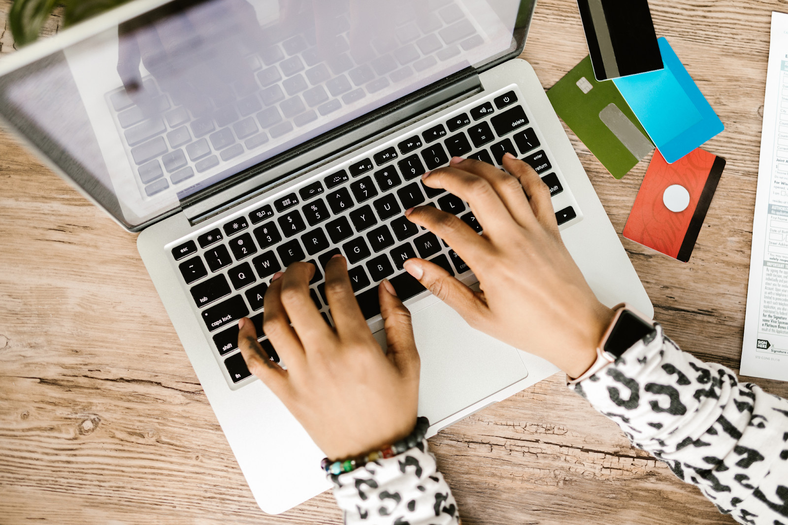 A person using a laptop with payment cards nearby, illustrating online transactions