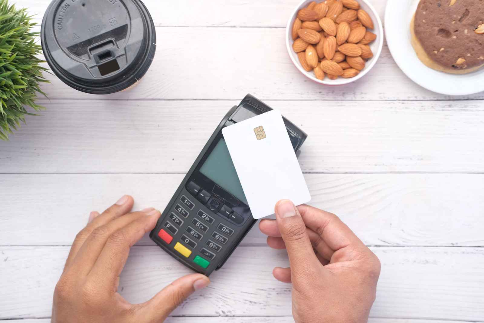 A person holding a chip-enabled payment card over a card reader in a store